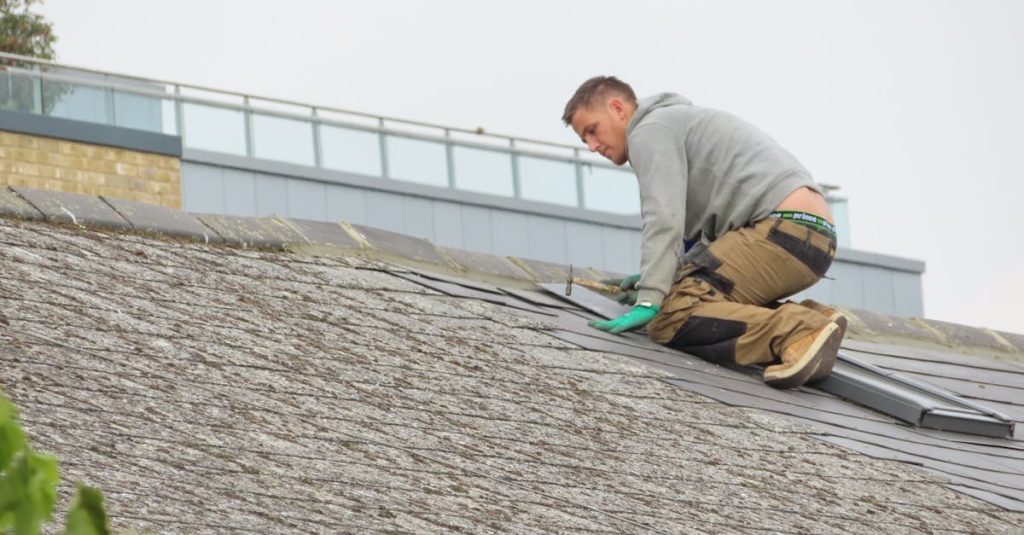 Construction worker installing shingles on a rooftop. Outdoor building maintenance.